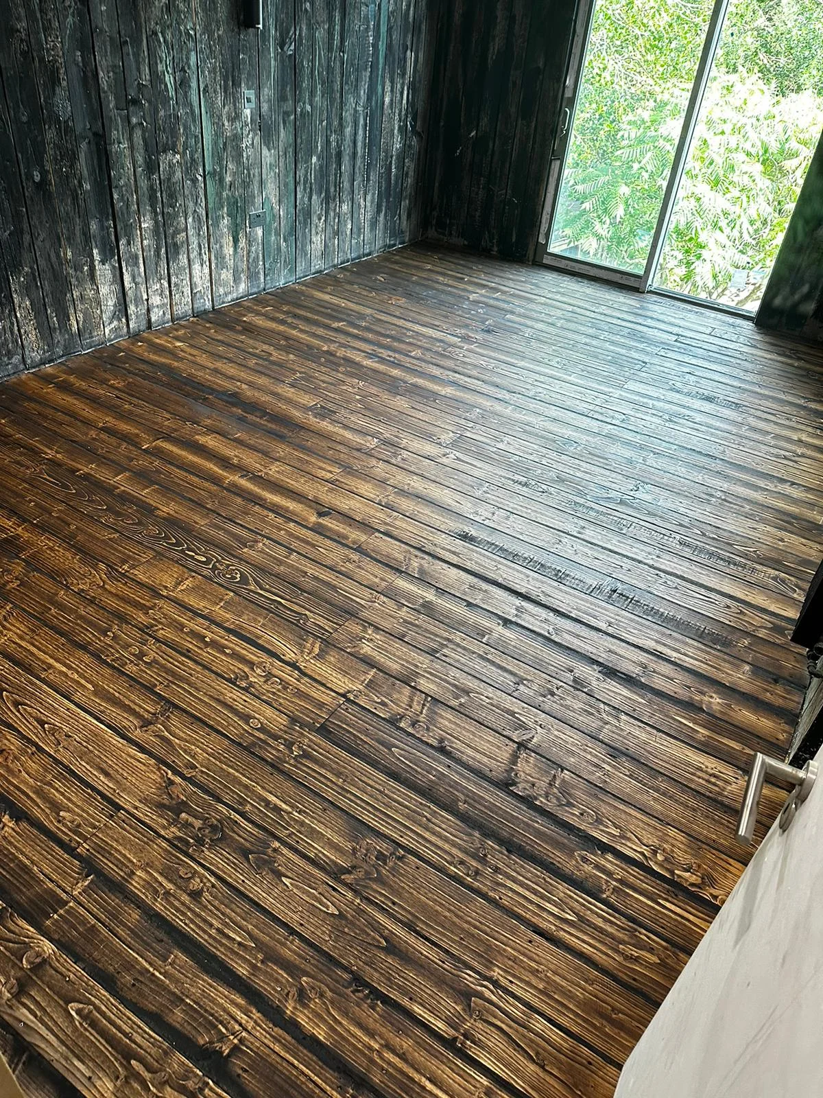 A very old wooden floor perfectly sanded & stained with a dark coat.