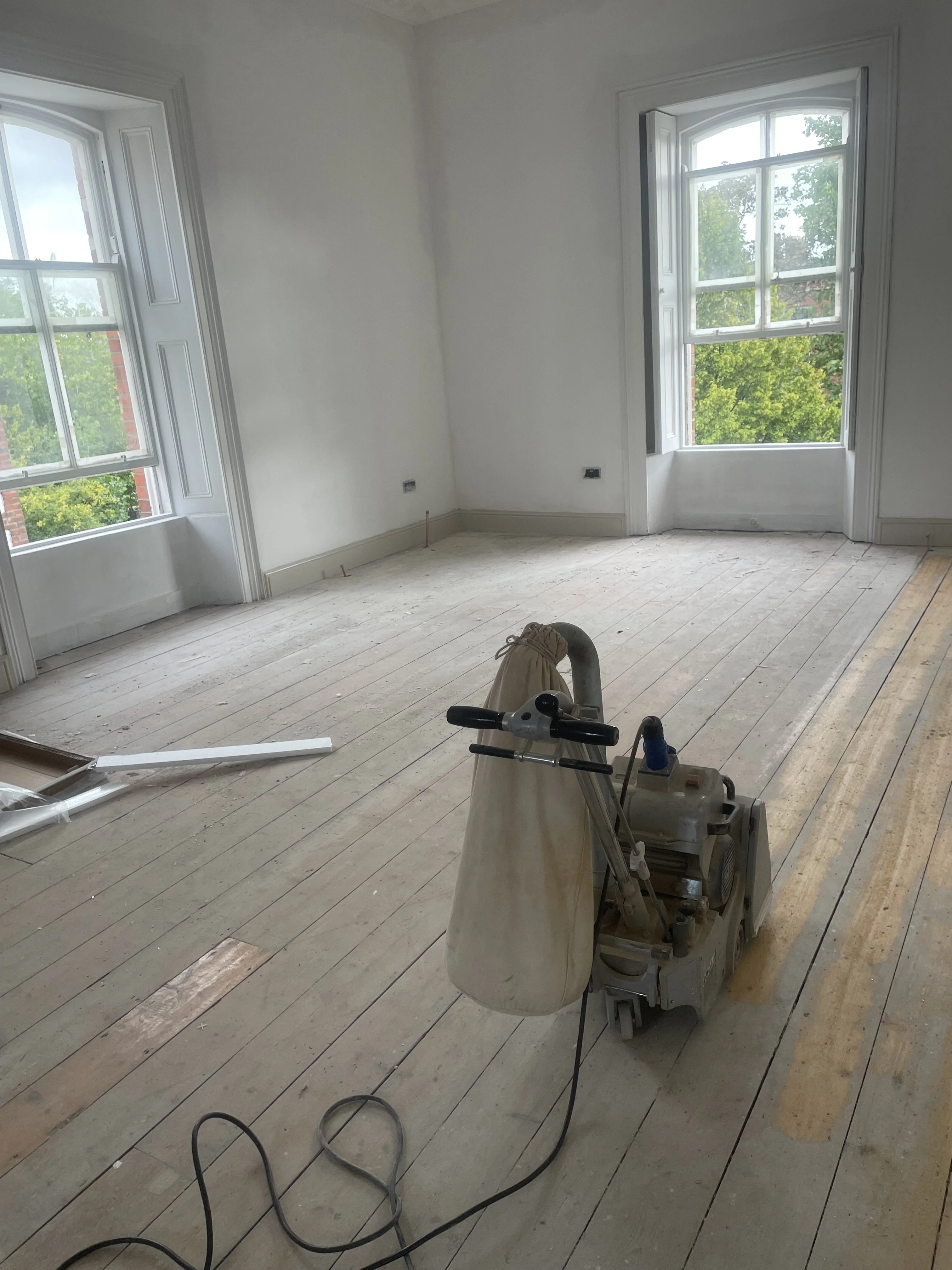 A wooden floor in the sanding process with a floor half sanded and half not sanded.