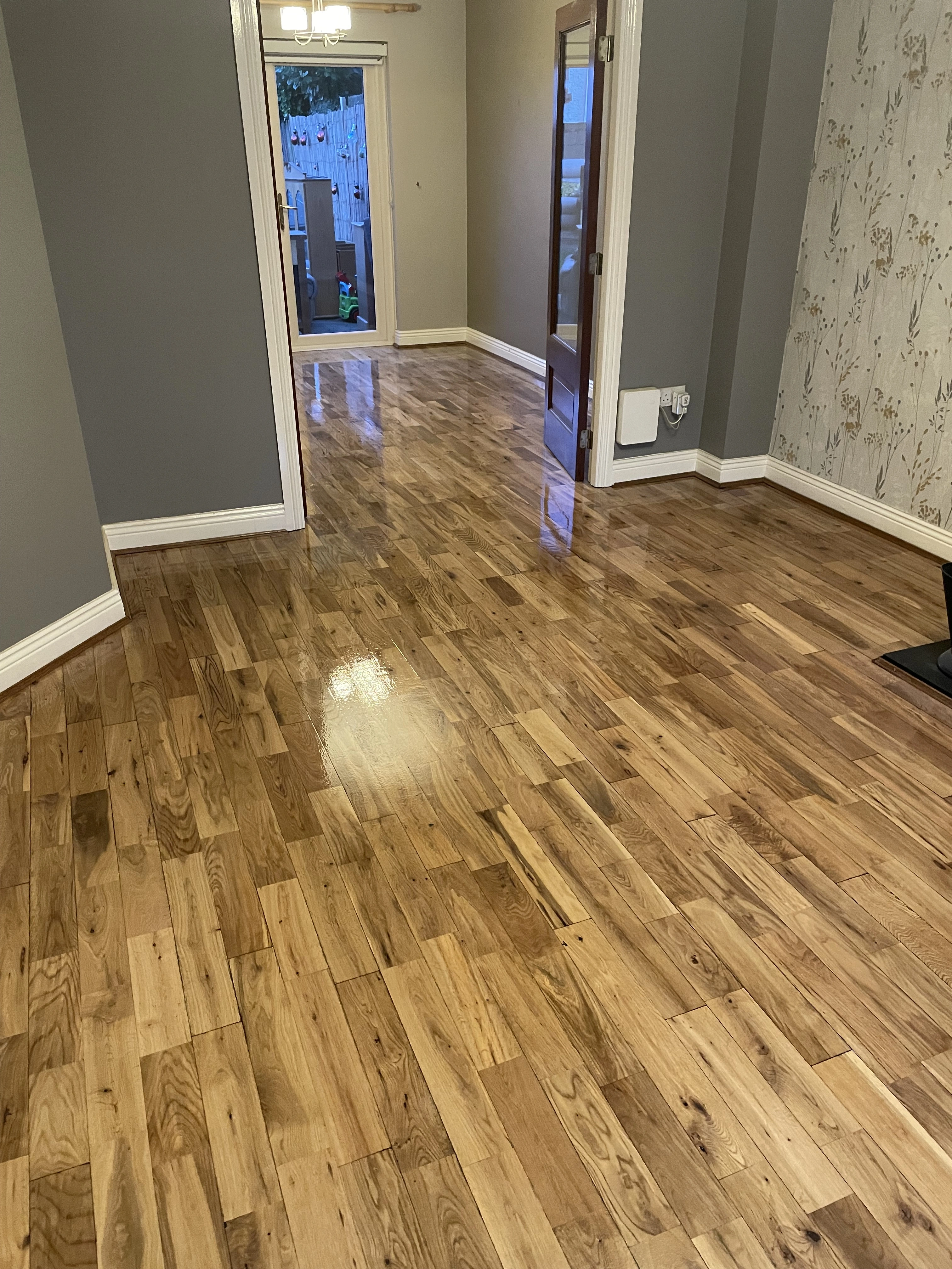 A perfectly stained & standed wooden floor with a gray walls and white floor covers.