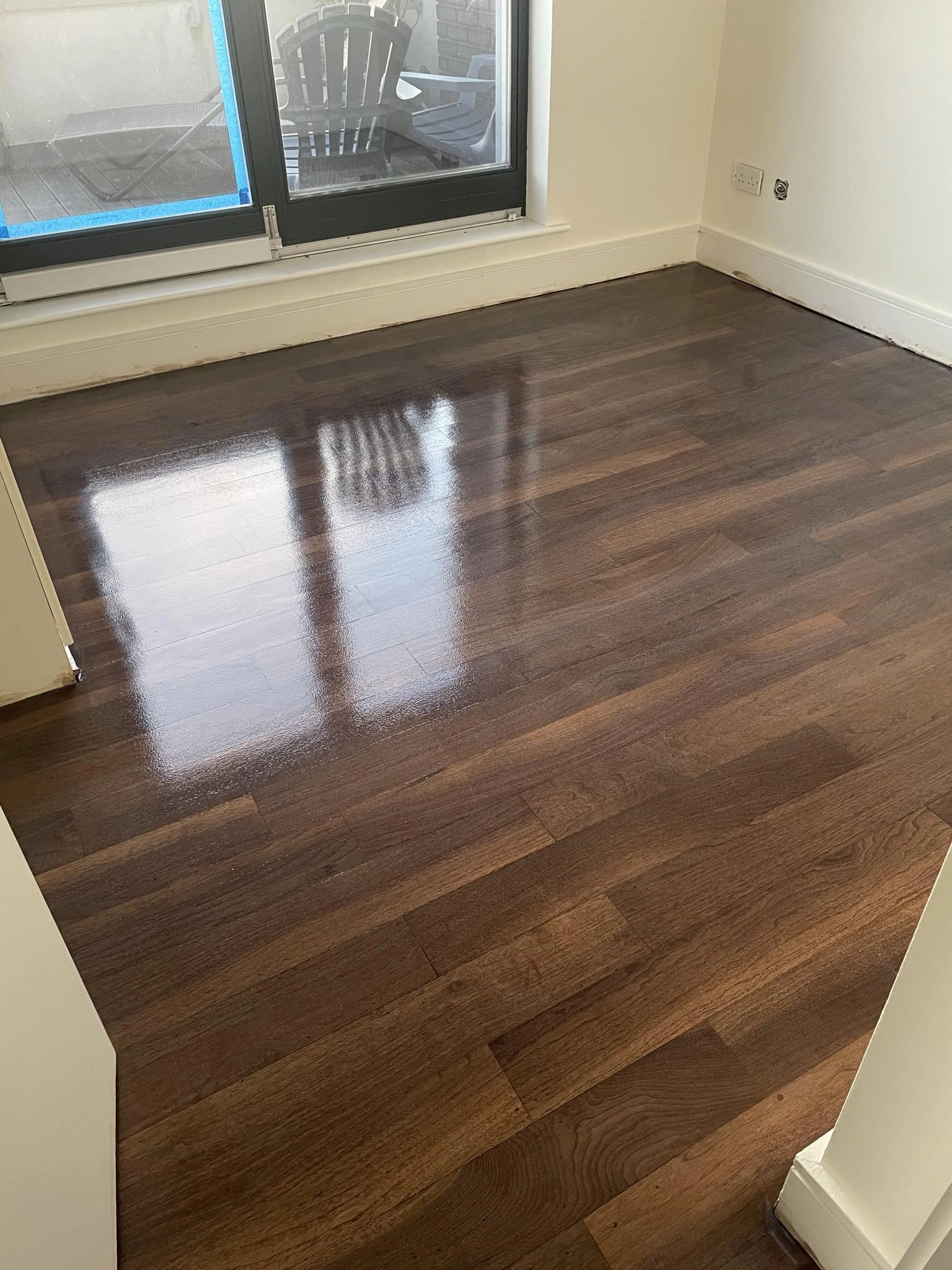 A dark semi-solid wooden floor sanded & stained with a nice coat.