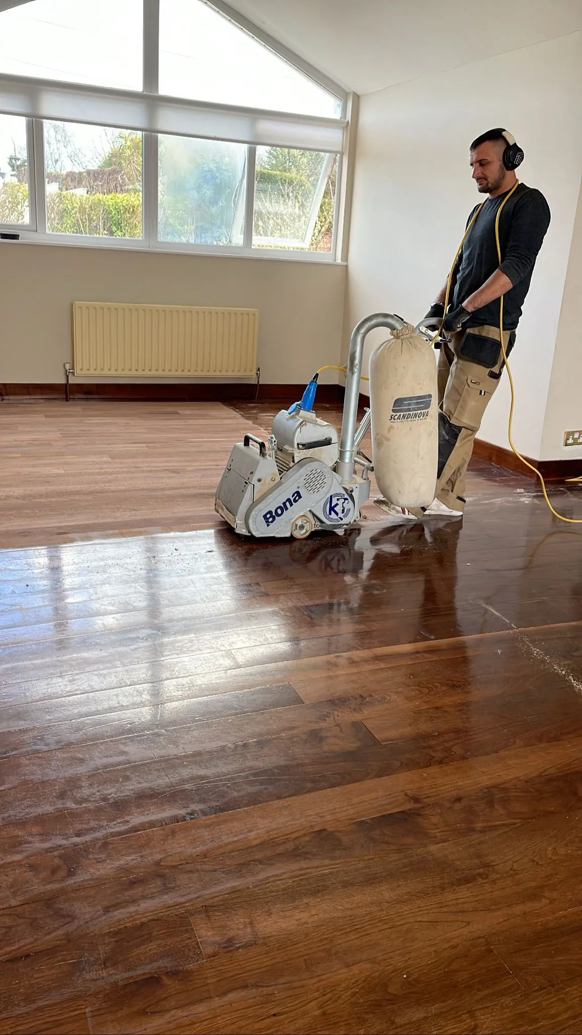 Alin in the process of sanding wooden floor.