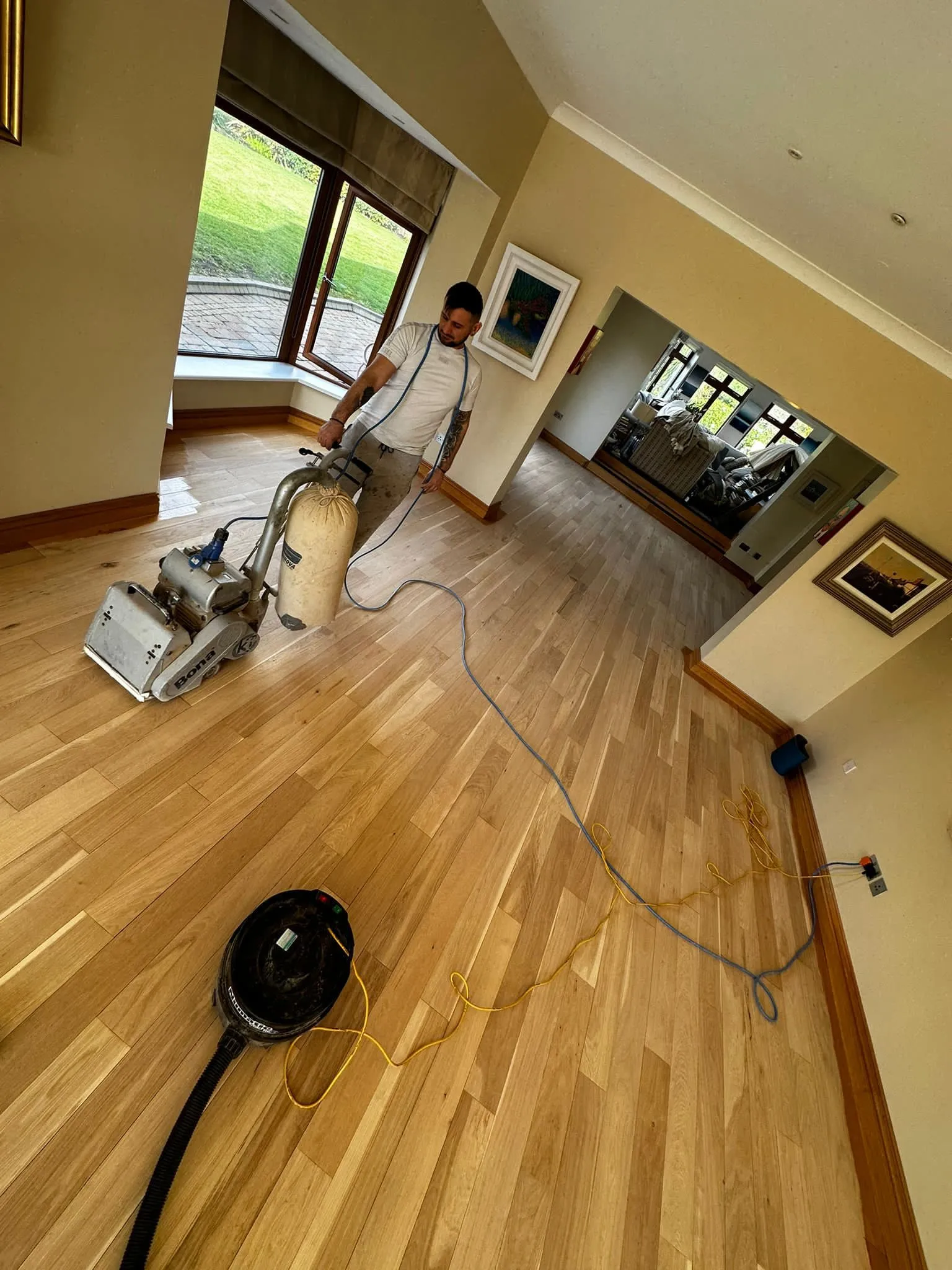 Alin in the process of sanding wooden floor.