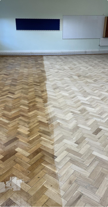 A class from a school with a wooden floor half sanded.